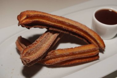 Churros, fincan sıcak çikolata ile tabakta kızarmış hamur pasta