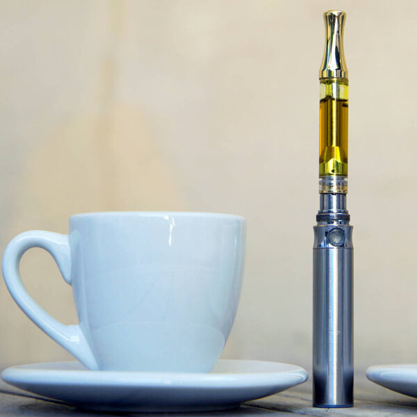 Vape Pen and cup on wooden surface, vaping marijuana oil, cannabis vaporizer 