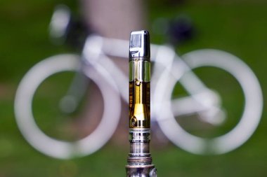 Electronic cigarette with cannabis oil on blurred natural background clipart