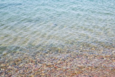 Göl kıyısındaki kumsalda suda taşlar 