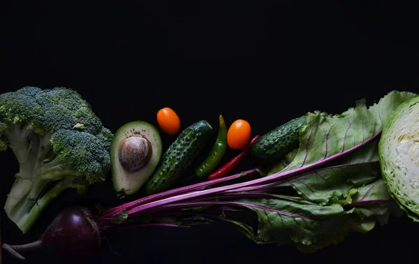 vegetables on the black background. Avocado, broccoli, cucumber, tomatoes, beetroot and green chili pepper. Vegan healthy food. Fresh organic ingredients.