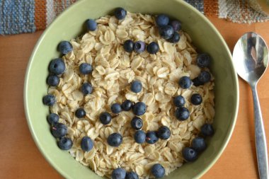 taze yaban mersini ile yulaf ezmesi. ahşap arka plan üzerinde yeşil kase organik tahıllar. vegan kahvaltı.