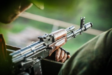 Askeri bir adam bir Ak-47 tutuyor