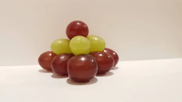 Kırmızı ve yeşil üzüm yığılmış bir piramit. Sanatsal tasarım. Meyve sanat ve el sanatları.