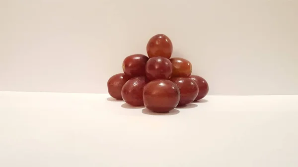 Kırmızı üzüm sanat ve el sanatları. Sanatsal meyve tasarım. Piramit şeklinde beyaz arka plan üzerinde.