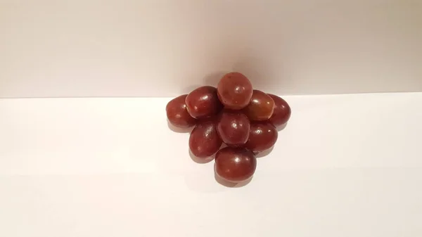 Kırmızı üzüm sanat ve el sanatları. Sanatsal meyve tasarım. Piramit şeklinde beyaz arka plan üzerinde.