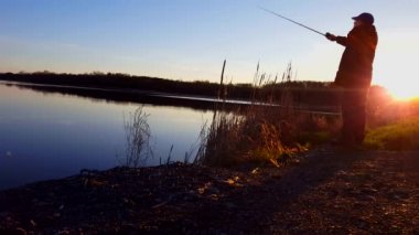 Erken sabah gündoğumu sırasında gölde adam balıkçılık. Güneş Shining Ile Dawn at Fishing Rod Ile kişi balıkçılık.
