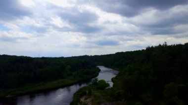 Bulutlu Yeşiller gökyüzü altında yemyeşil ormanlar ile çevrili sakin akan nehrin yüksek açı görünümü.