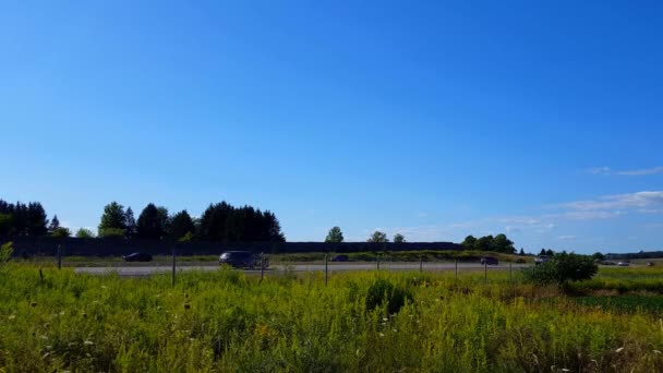 明るい夏の日の農村高速道路の側面図 州間と緑豊かな草の上に高速移動車のトラフィックと美しい風光明媚な風景 — ストック動画