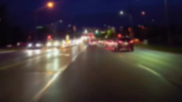ぼかし効果で夜に市街地を運転 夕方の交差点を走行中の都市交通のドライバー視点Pov — ストック動画