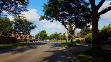 Kentin varoşlarında yaya insanlarla dolu bir kavşak ve yazın trafiği var. Şehir Banliyö Araçlarında Sürücü ve Arabalar Gün Boyunca Trafik Işığı Kavşağından Geçer.