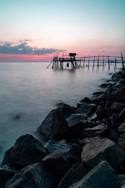 ahşap iskelesi ile kayalık deniz günbatımı sırasında. Uzun pozlama dikey yönlendirme