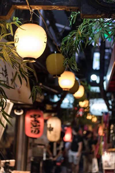 Seçici odak. Shinjuku 'daki Omoide Yokocho 'da fenerle asılı. Dikey oryantasyon.