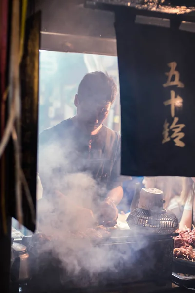 Restoranda işçi, geleneksel bar Omoide Yokocho, Shinjuku müşteri için yiyecek hazırlamak. Dikey oryantasyon.