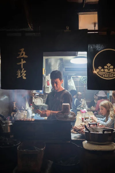 Trabalhador do restaurante preparando a comida para o cliente no bar tradicional em Omoide Yokocho, Shinjuku. Orientação de Retrato . — Fotografia de Stock