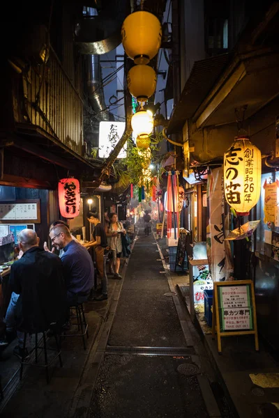 Gece Omoide Yokocho 'da sokak görünümü. Geleneksel Japon binası. Dikey oryantasyon.