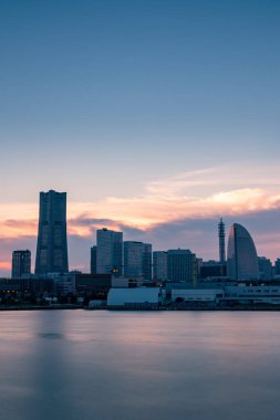 Gün batımında Minato Mirai ufuk çizgisi, denizdeki yansımasıyla. Uzun pozlama.