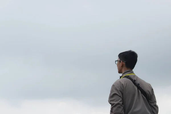 曇り空を眺めているアジア系の男性の肖像画です ロイヤリティフリーのストック写真