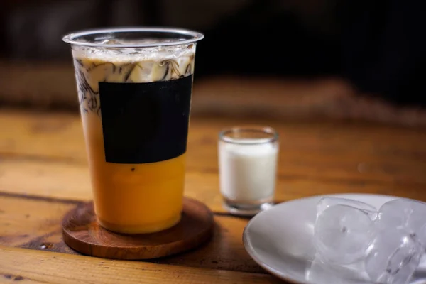 Süt ve çimen jölesi karışımı koyu arkaplanlı mango buzu. Meyve aromalı soğuk içecekler. Plastik bardaklarla renkli buz modelleri