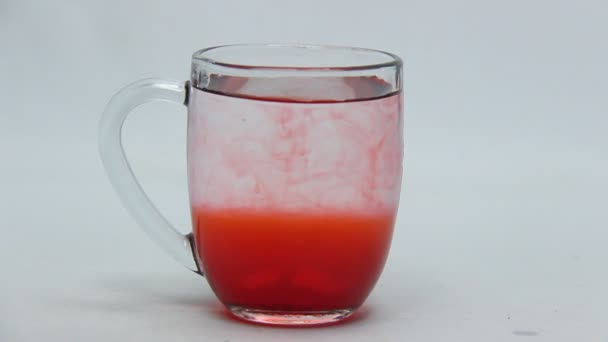 染料の液体と混合したガラス中のミネラルウォーター 水と食品着色料やケーキを混ぜる実験です 赤い液体混合物 — ストック動画