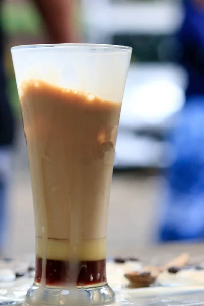 Ahşap bir kafe masasında bir fincan buzlu sütlü kahve. Gün içinde kahve molası için taze kahve yap.