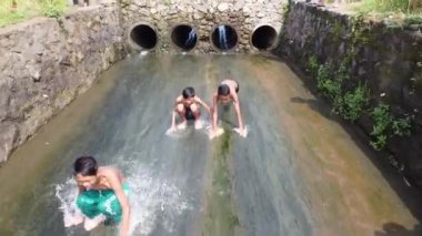 Endonezyalı gençler sığ nehirlerde su kayağı yapıyorlar. Kırsal kesimde basit ve heyecan verici bir oyun. Mojokerto, Endonezya. Mart 2020