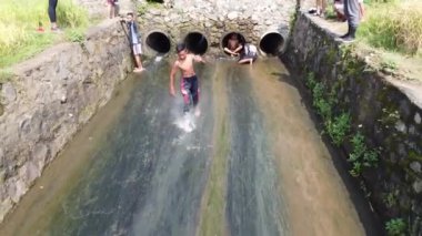 Endonezyalı gençler sığ nehirlerde su kayağı yapıyorlar. Kırsal kesimde basit ve heyecan verici bir oyun. Mojokerto, Endonezya. Mart 2020