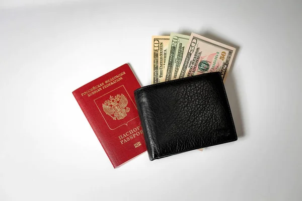 Billetes de dólar en una cartera de hombre negro sobre un fondo blanco y un pasaporte de la Federación Rusa — Foto de Stock