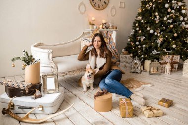 sıcak bir ceket kanepe önünde oturan ve Galce Corgi hırka, hediyeler dikkate alınarak bir köpekle oynayan bir kız