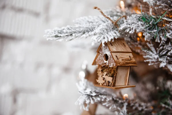 Christmas tree toy house hanging on a Christmas tree on the background of a white brick wall in the loft