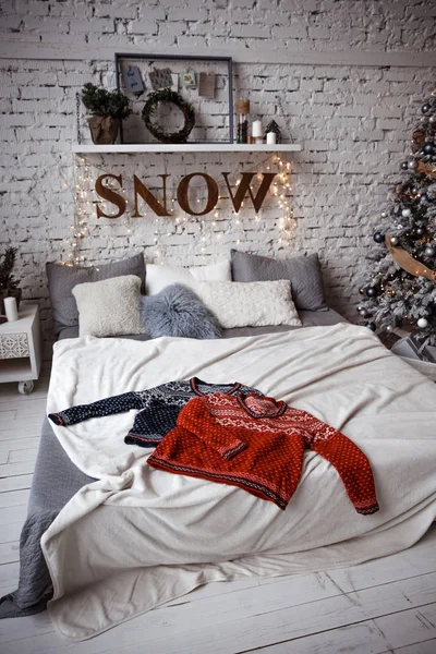 在一棵新年树旁的砖墙的背景下 有两件冬衣放在阁楼上的一张床上 — 图库照片