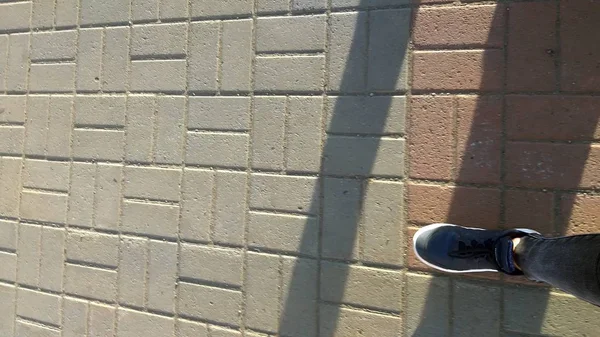Sneakers nere su asfalto e luce solare — Foto Stock