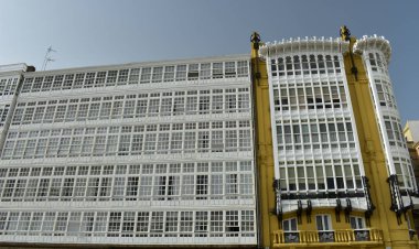 Pencere eşiği ile beyaz ahşap galerileri ve köşedeki sarı modernist evde. Cephe detayları, ahşap, cam, siyah demir, balkon ve küpeşte. Güneşli bir gün, mavi gökyüzü. La Coruna, İspanya.