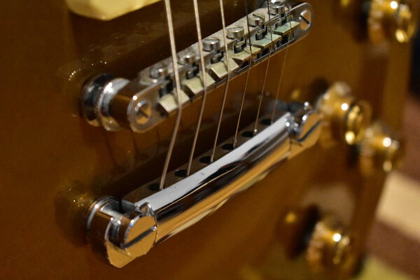 Gold top electric guitar closeup. Bridge, strings and knobs details.