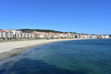 Plaj ve kıyı köyü turkuaz su ve altın kum ile. Güneşli bir gün, mavi gökyüzü, yeşil ve mavi su renkler. Temiz su. Sanxenxo, Galiçya, İspanya.