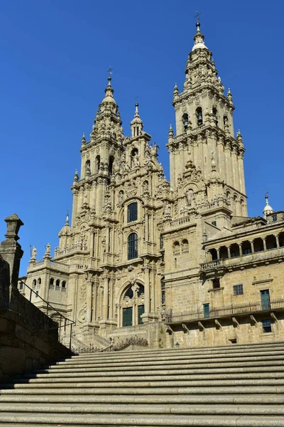 Cathedral, side view from stairs. Obradoiro Square, baroque facade with clean stone. Sunny day, blue sky. Santiago de Compostela, Spain.