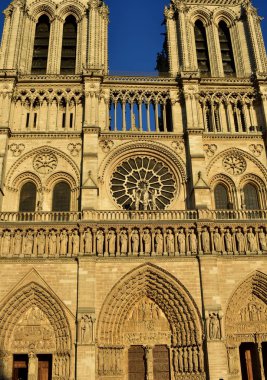 Notre Dame Katedrali, Paris, Fransa. Gotik cephe gülümsemek günbatımı ışığı ile. Kuleleri, heykeller, gül pencere, gözlerden ve kapılar.