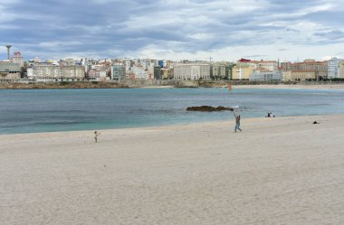Father and little girl playing on Riazor Beach with a kite. La Coruna, Spain. clipart