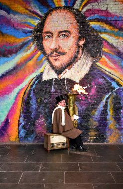 Bir sokak müzisyen bir tuba önünde bir duvar grafiti ile semt pazarında ateşle oynuyor. London, Büyük Britanya.