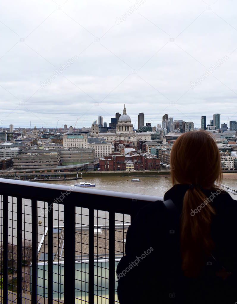 Woman looking at St Pauls Cathedral from Tate Modern lookout. London, United Kingdom.