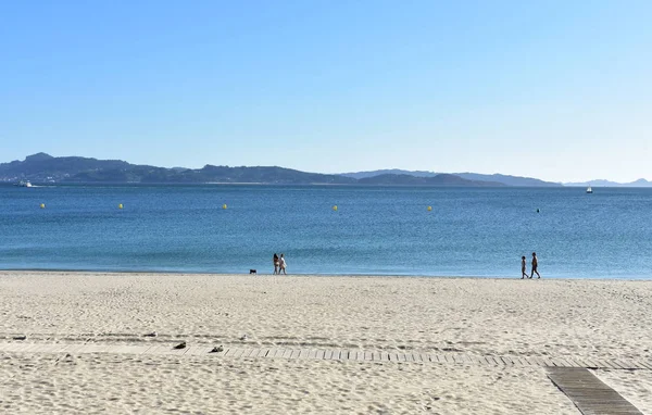 ビーチ歩行の犬を持つ人々 船と海の青 澄んだ空 晴れた日 サンシェンショ ガリシア スペイン — ストック写真