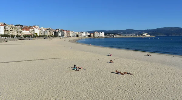 ビーチでの日光浴の人 明るい砂浜と青い海 晴れた日に サンシェンショ ガリシア スペイン — ストック写真