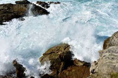 Vahşi dalgalar kayalara karşı sıçramasına. Mavi deniz beyaz köpük, Galiçya, İspanya.