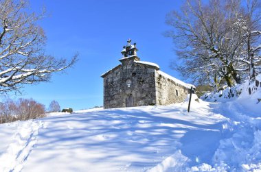 Piornedo, Lugo, İspanya. San Lorenzo Hermitage kar, buz ve buz sarkıtları ile. Güneşli bir gün, ağaçlar ve mavi gökyüzü.