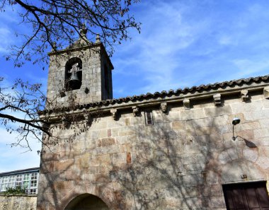 Romanesque medieval San Esteban Church. Bell tower and tree, side view. Allariz, Orense, Spain. clipart