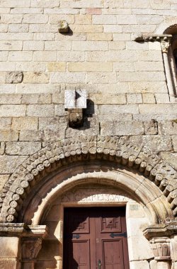 Güneş saati çalışıyor. Ortaçağ Romanesk San Pedro kilise, taş duvar ve kemerli kapı. Allariz, Toledo, İspanya.