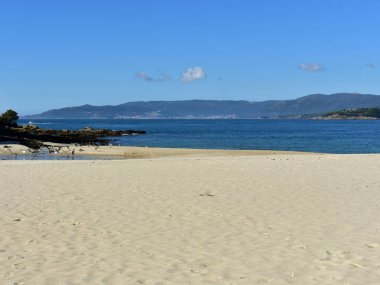 Parlak kum, martılar ve mavi gökyüzü ile plaj. Galiçya, İspanya.
