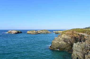 Çim ve adalar, mavi deniz ve güneşli bir gün ile Uçurum. Galiçya, İspanya.