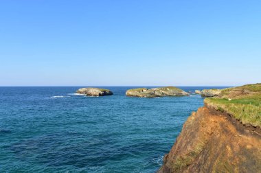 Çim ve adalar, mavi deniz ve güneşli bir gün ile Uçurum. Galiçya, İspanya.