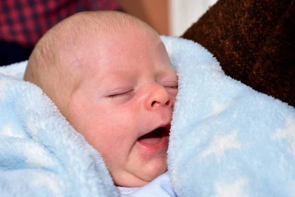Newborn baby with a blue blanket. Blonde boy.